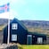 Un edificio en medio de los fiordos occidentales con la bandera de Islandia ondeando afuera